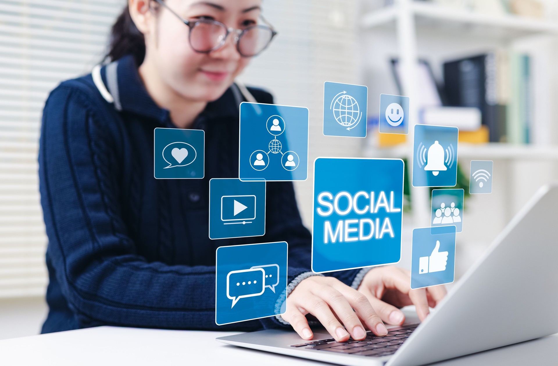 Social media networking and communication concept. Woman using laptop with social media icons, chat, likes, notifications, video, representing digital networking, engagement, and online interaction.
